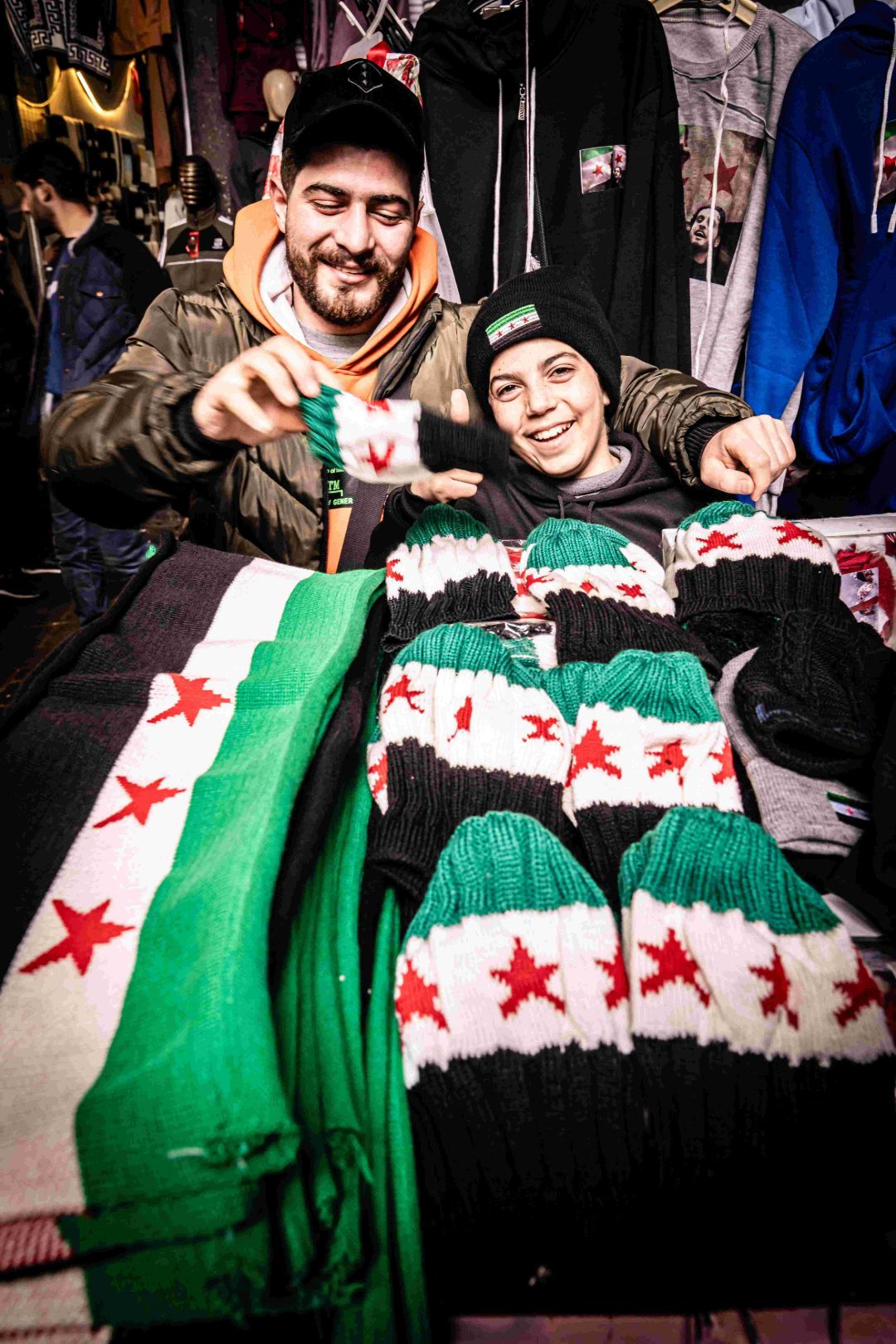 Vater und Sohn mit Strickschals mit syrischer Flagge auf dem Markt