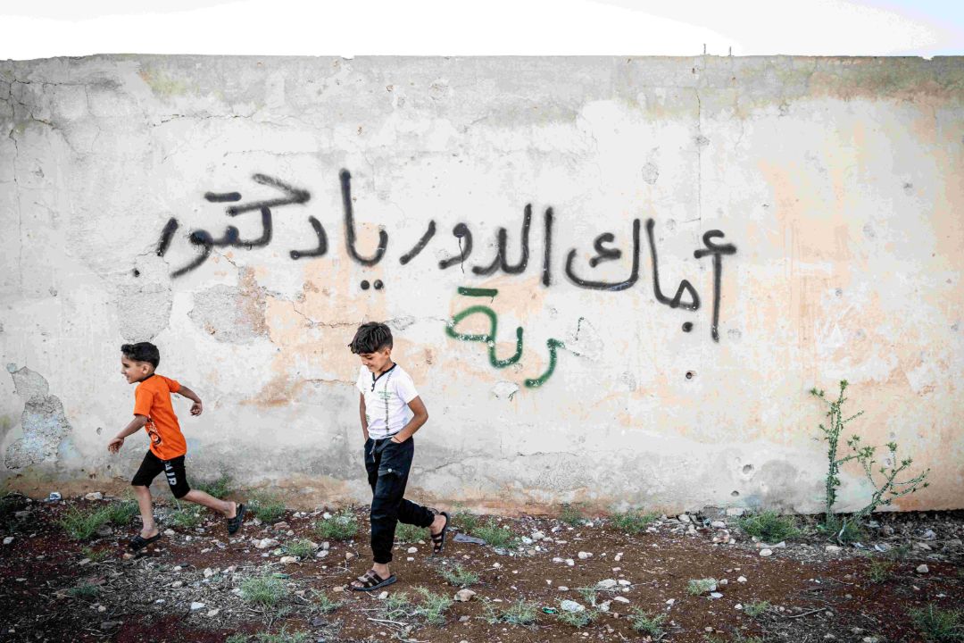 zwei Jungen vor einem arabischen Graffiti zum Thema Liebe