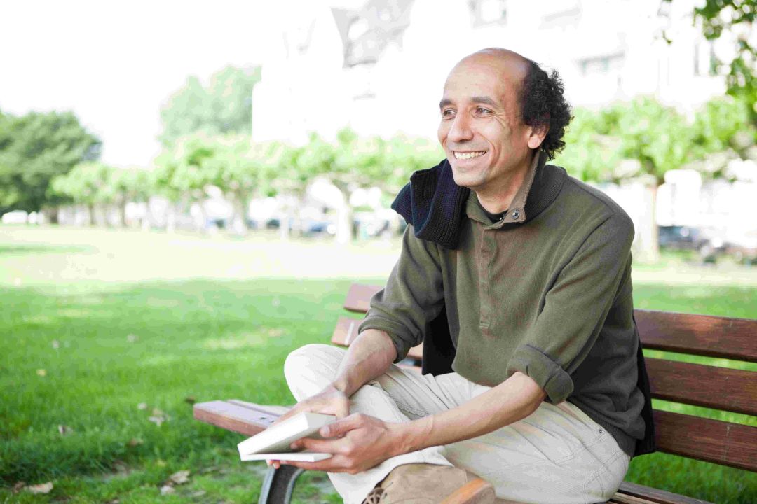  Referent Josef Schoenen sitzt mit Buch auf einer Parkbank