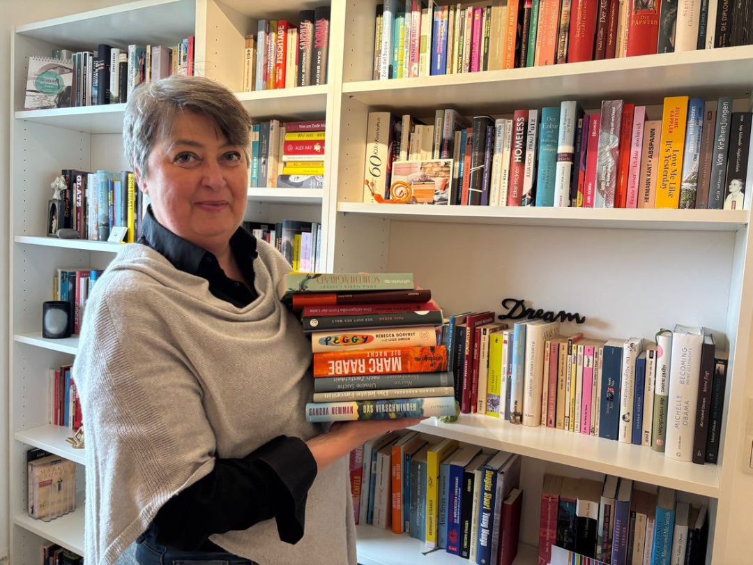 Frau Quint mit einigen B&uuml;chern in der Hand vor einem B&uuml;cherregal