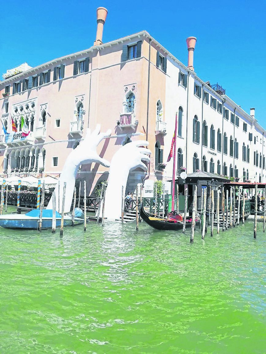 Geb&auml;ude in Venedig vom Wasser aus fotografiert mit zwei H&auml;nden, die aus dem Wasser ragen