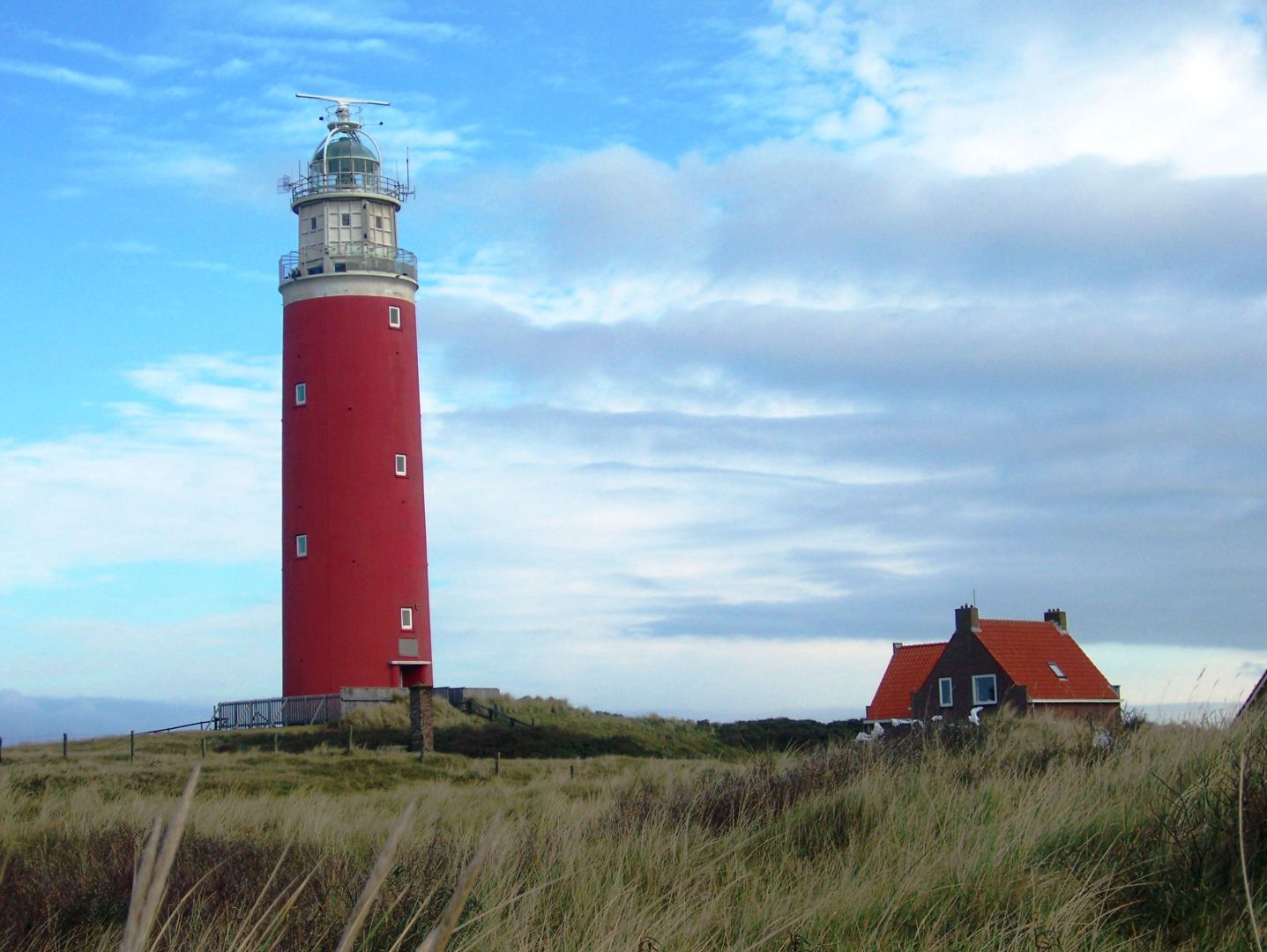 roter Leuchtturm mit kleinem roten Haus daneben, in den D&uuml;nen